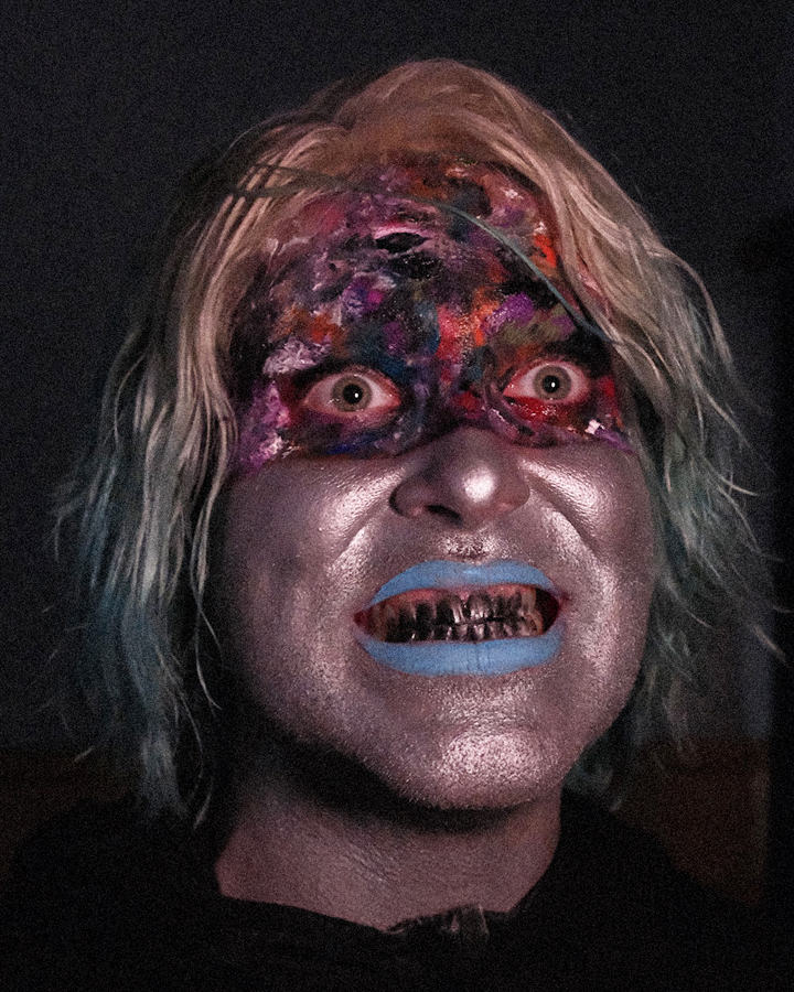Close up portrait of Jules Crosby with Will Weisenfled with frightening makeup and blacked out teeth smiling at the camera